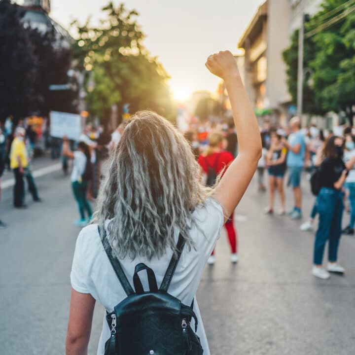 Young woman with a raised fist protesting in the street