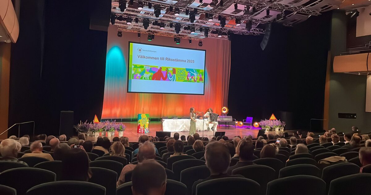 Scen med kvinnlig moderator som talar till publiken