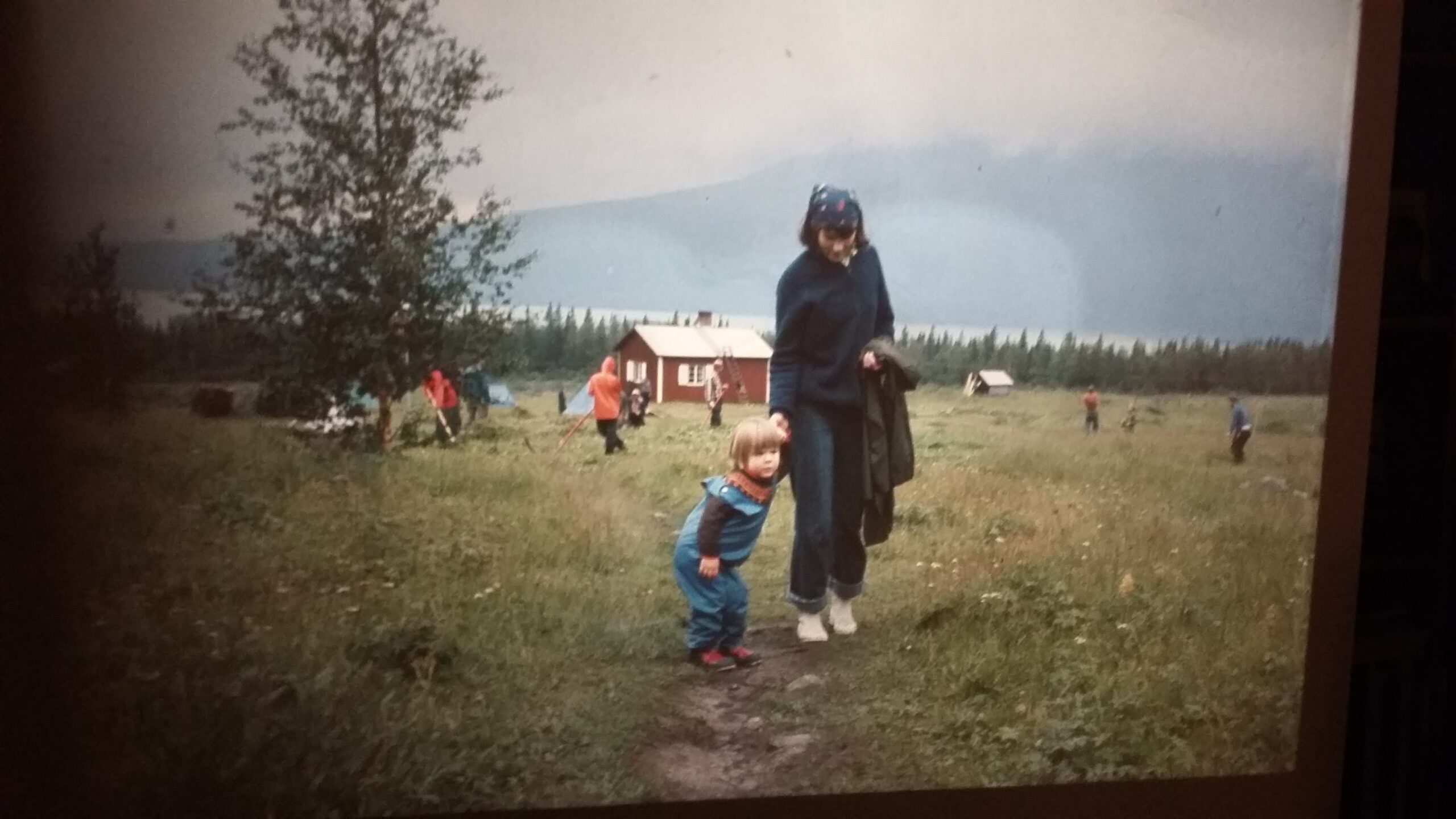 Barn med mamma framför fjällstuga