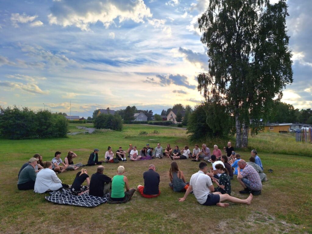 Människor sitter i en cirkel på en gräsmatta
